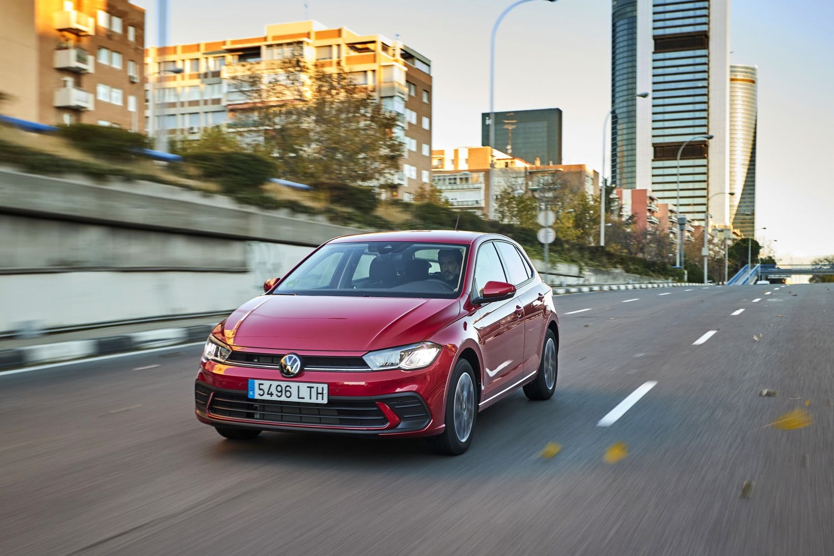 Volkswagen Polo circulando en una zona urbana, con arquitectura contemporánea.