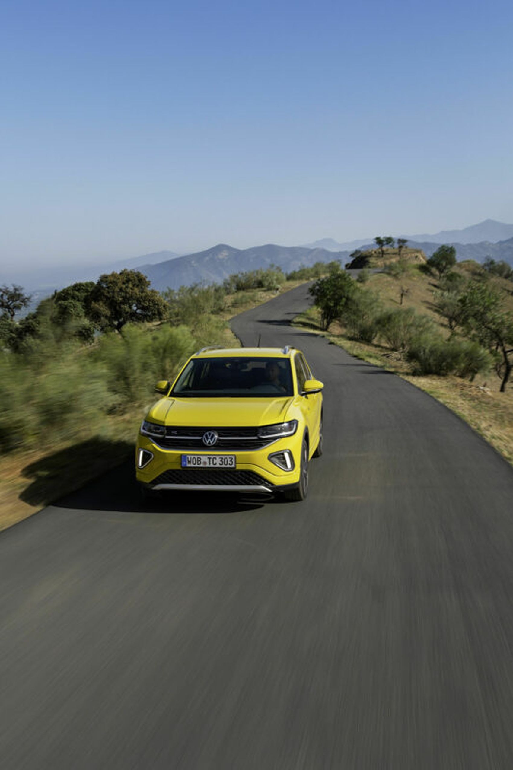 T-Cross amarillo en acción en una carretera montañosa, perfecto para aventuras.