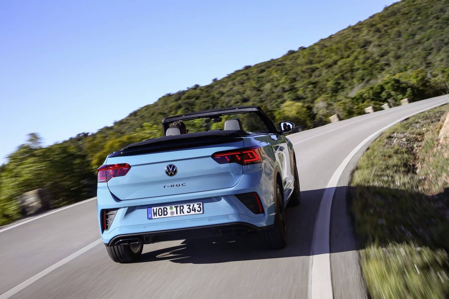 Vista trasera del T-Roc Cabrio en conducción, mostrando líneas y diseño de luz.