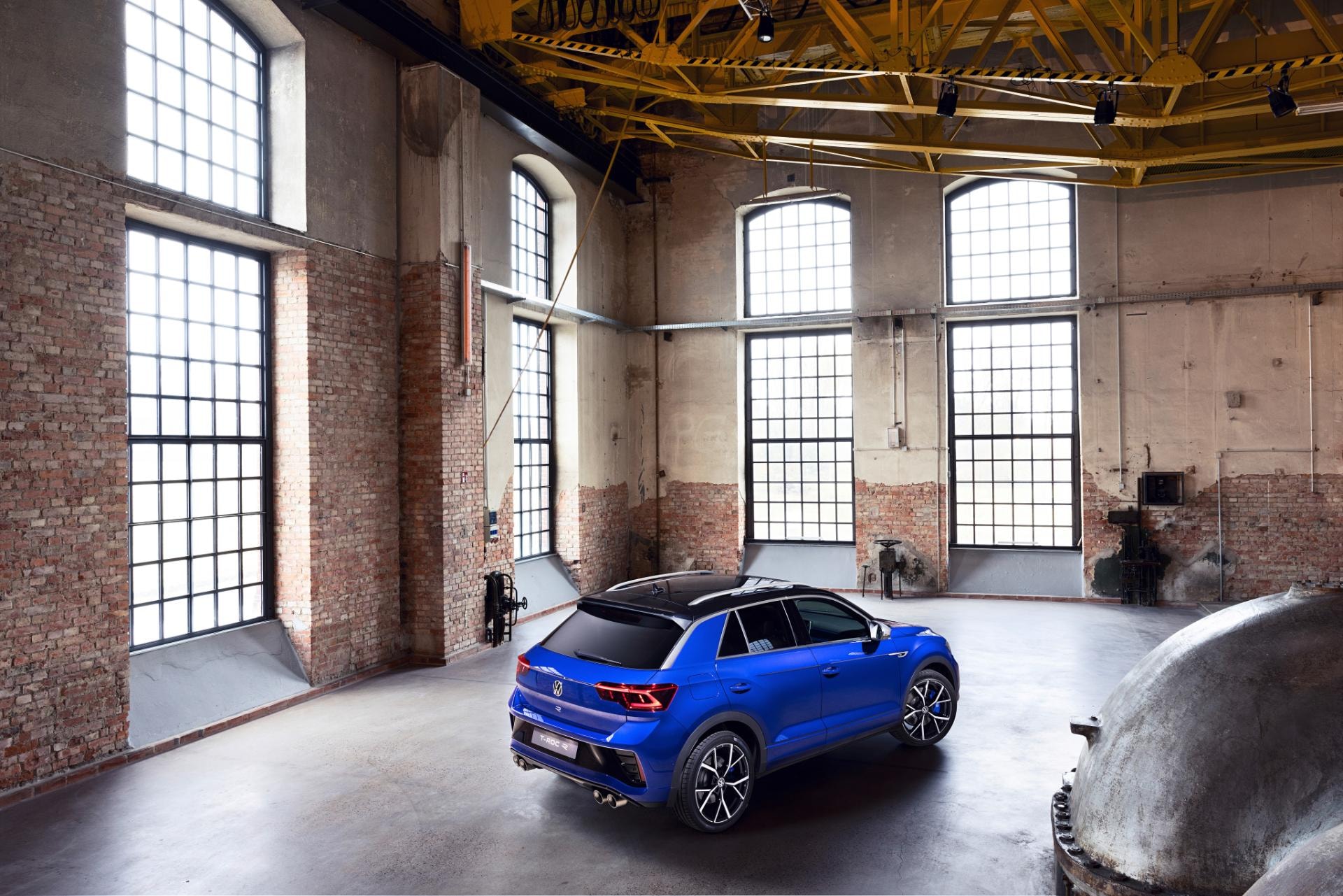 Perspectiva trasera y lateral del Volkswagen T-Roc R en un entorno industrial.