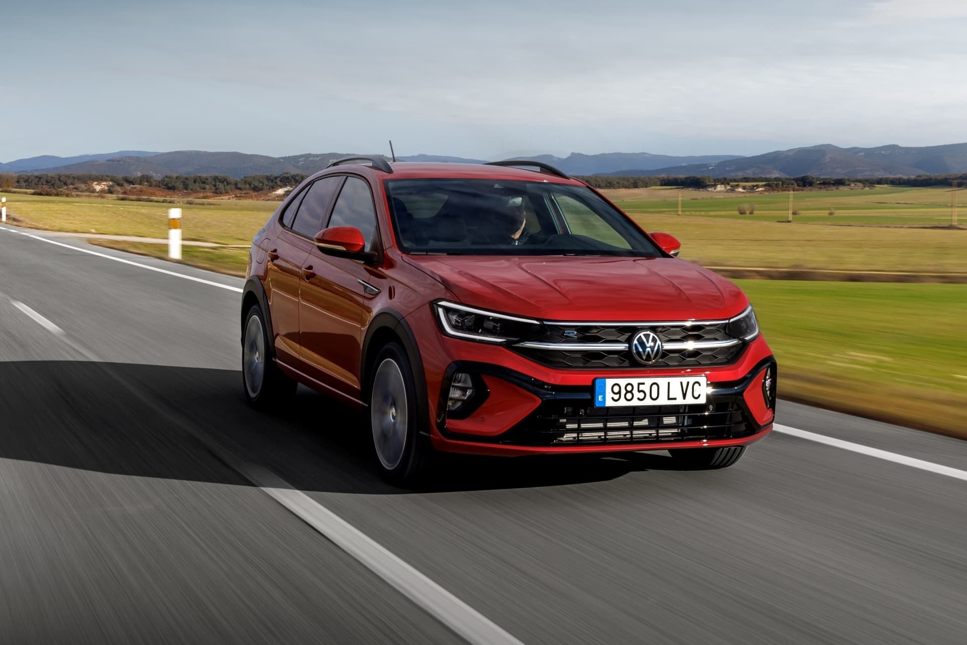 Vista dinámica del Volkswagen Taigo en tono rojo brillante, enfocando su lado delantero.