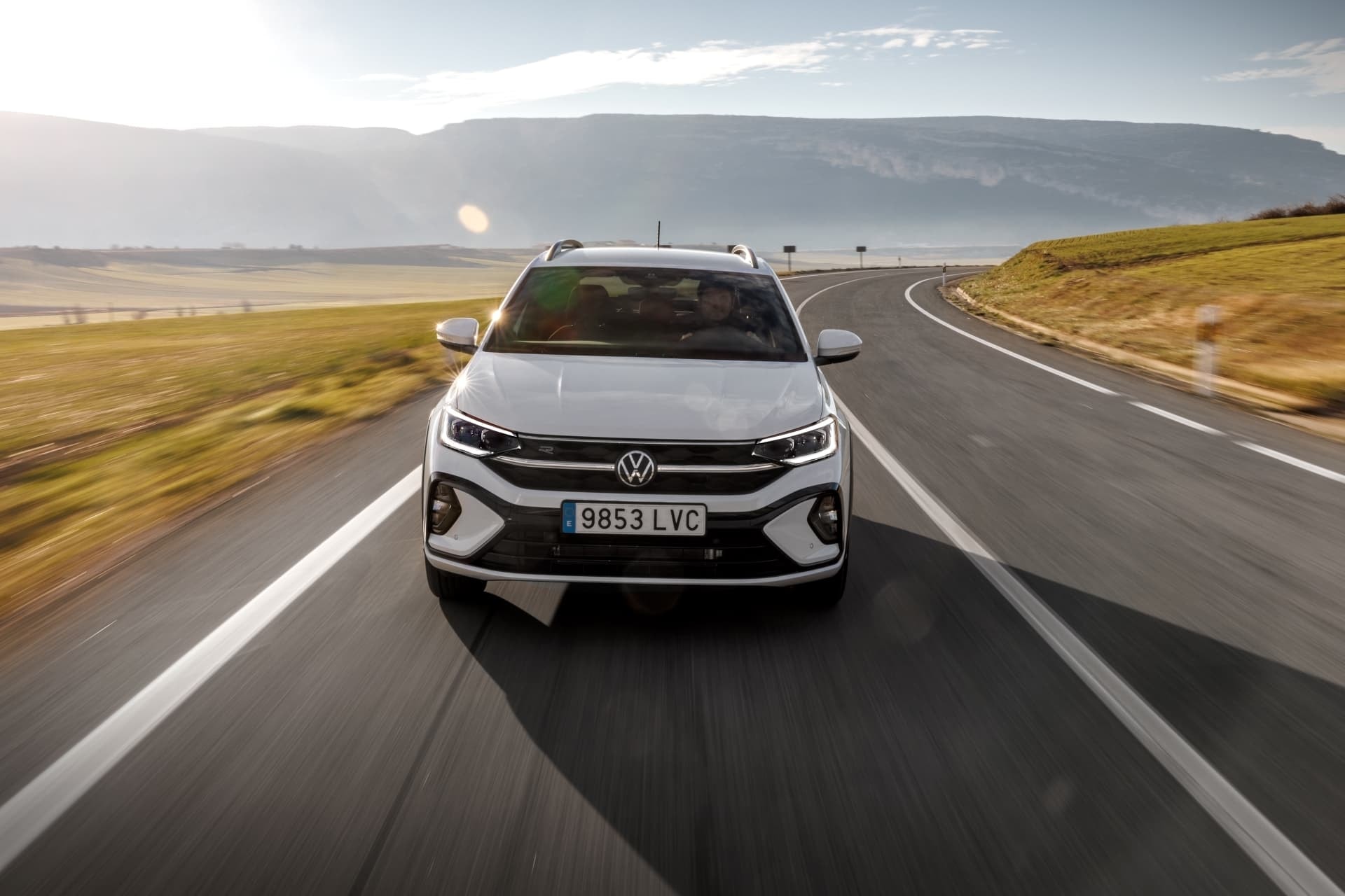 Vista frontal dinámica del Volkswagen Taigo blanco en carretera abierta.
