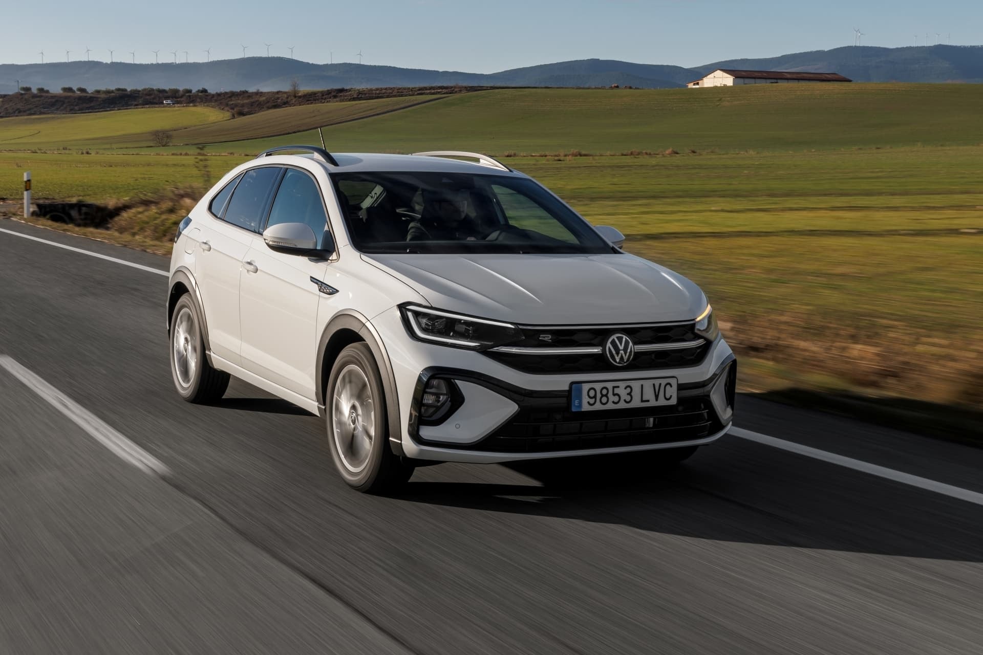 Volkswagen Taigo blanco en carretera, vista delantera lateral en acción.