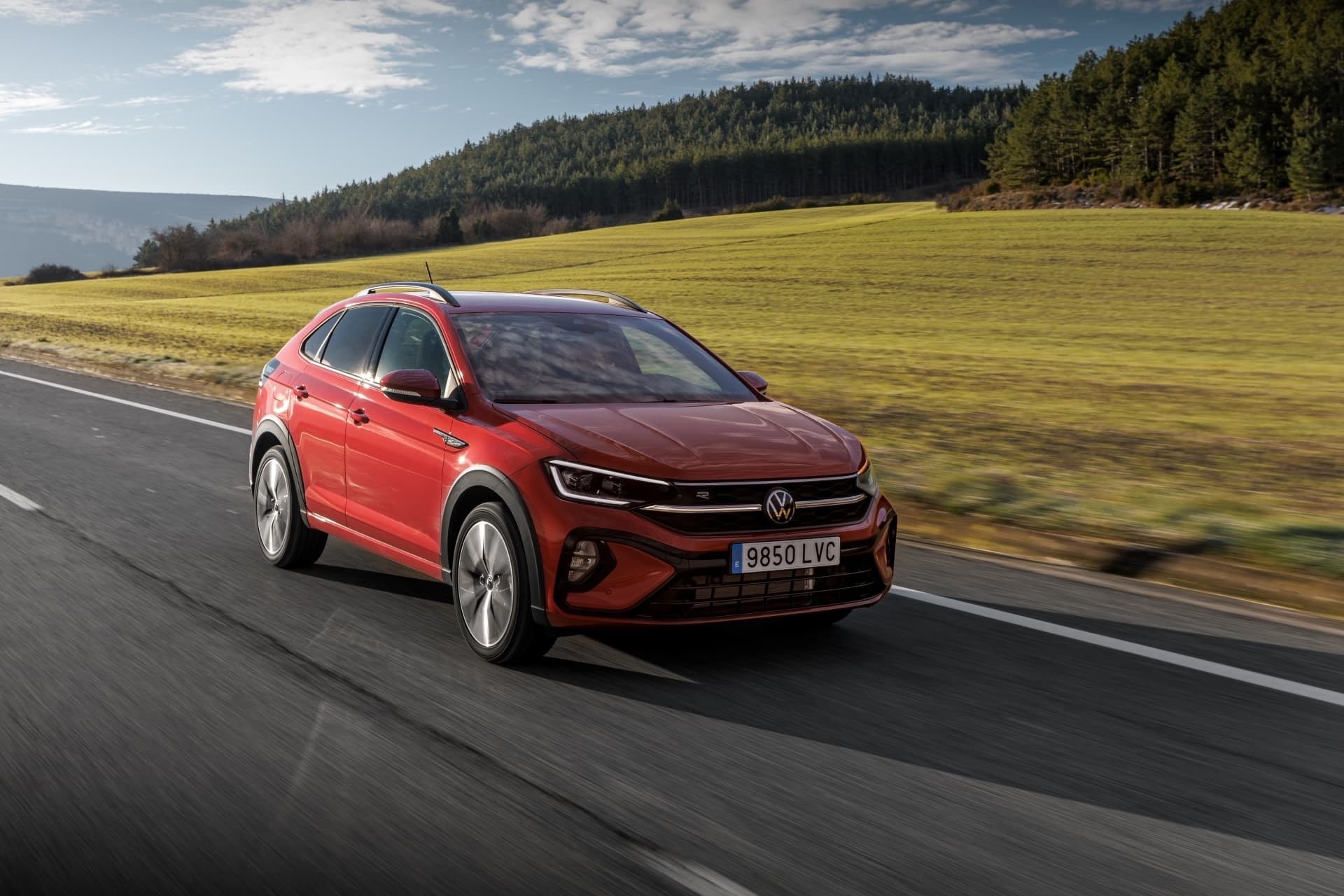 Volkswagen Taigo rojo recorriendo carretera, ángulo delantero lateral.