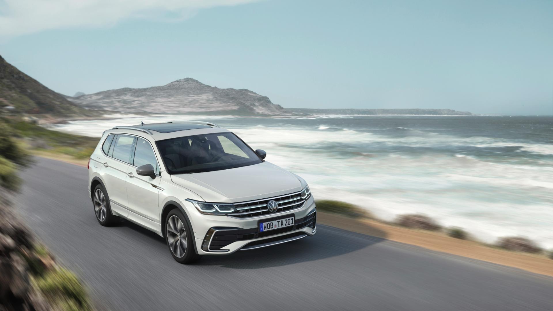 Volkswagen Tiguan Allspace en carretera costera, destacando su diseño y aerodinámica.