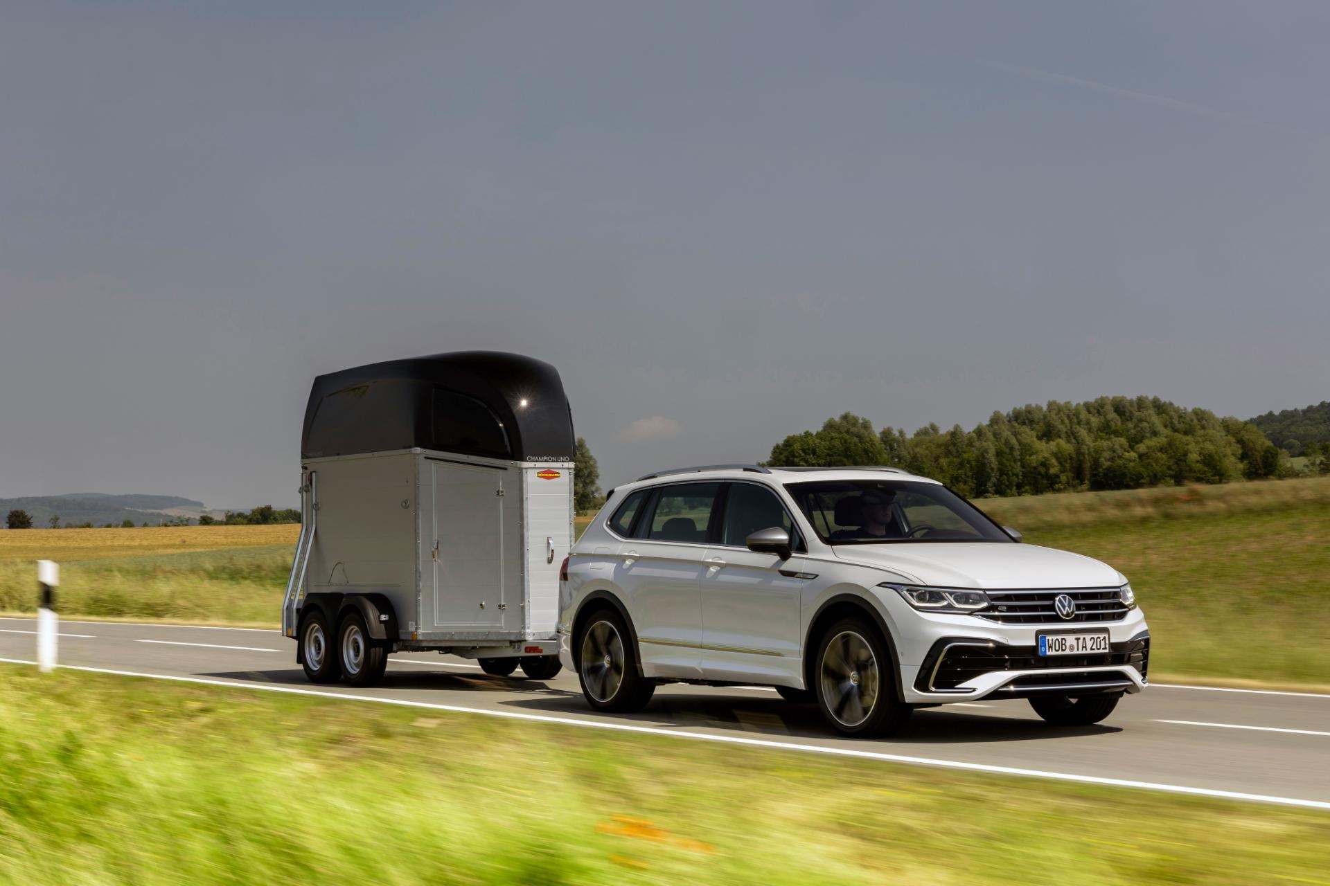 Vista lateral del Tiguan Allspace blanco remolcando, realza versatilidad para aventuras.