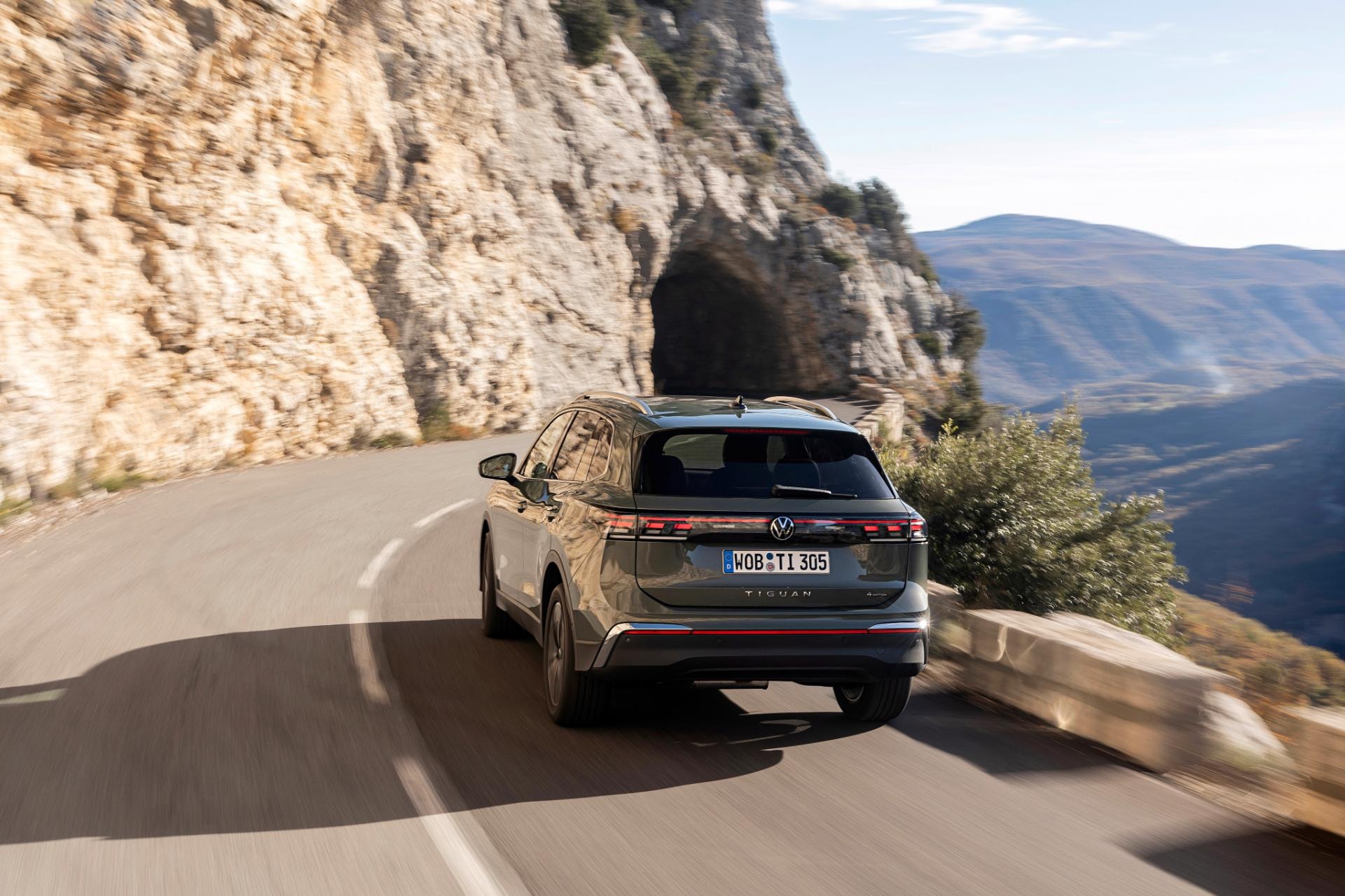 Tiguan híbrido mostrando su perfil en una carretera con curvas.