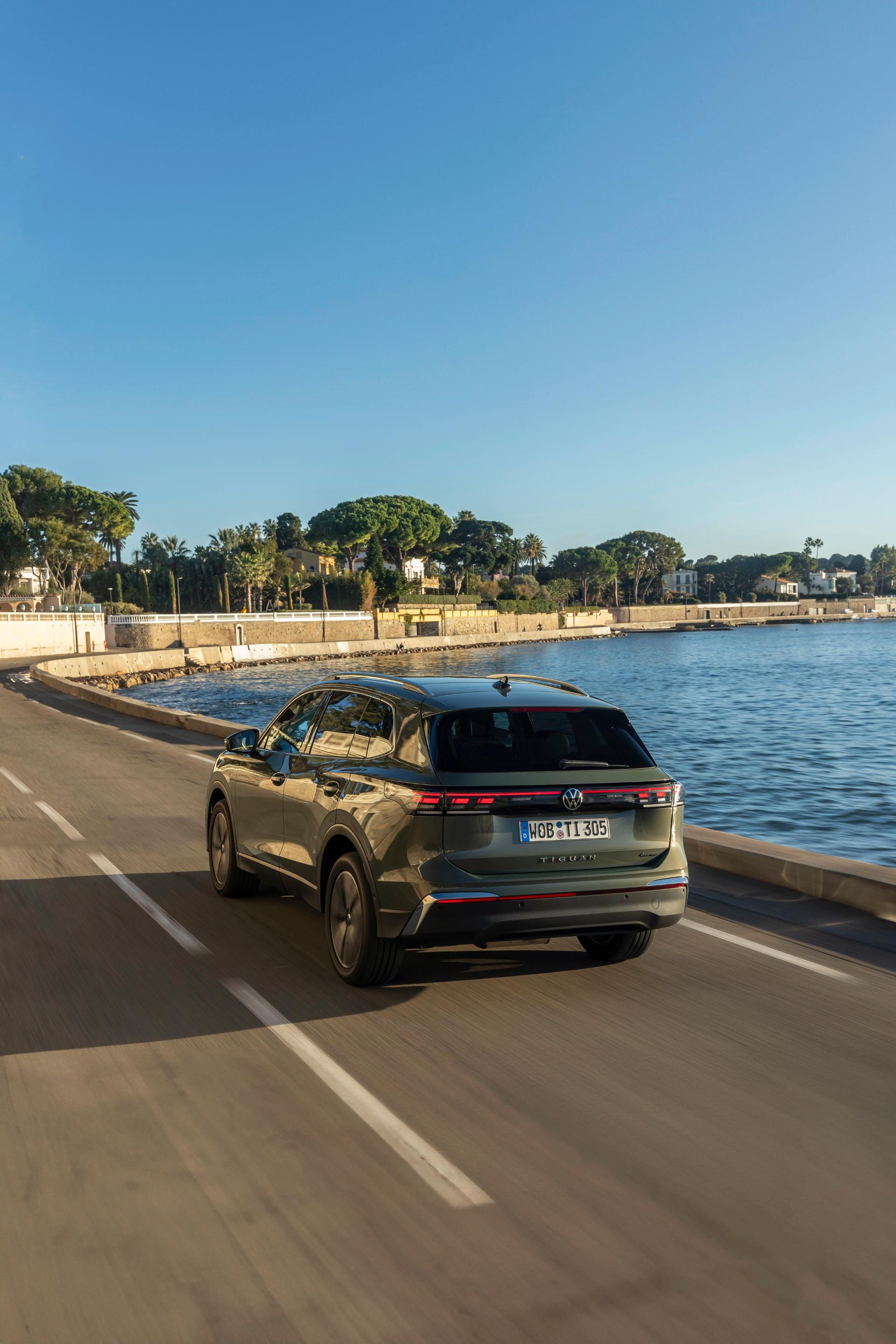 El Tiguan híbrido en movimiento cerca del agua, ideal para viajes costeros.