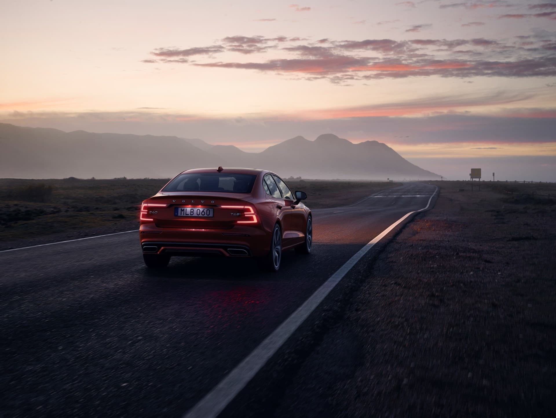 Volvo S60 en carretera al atardecer, enfatizando su diseño trasero.