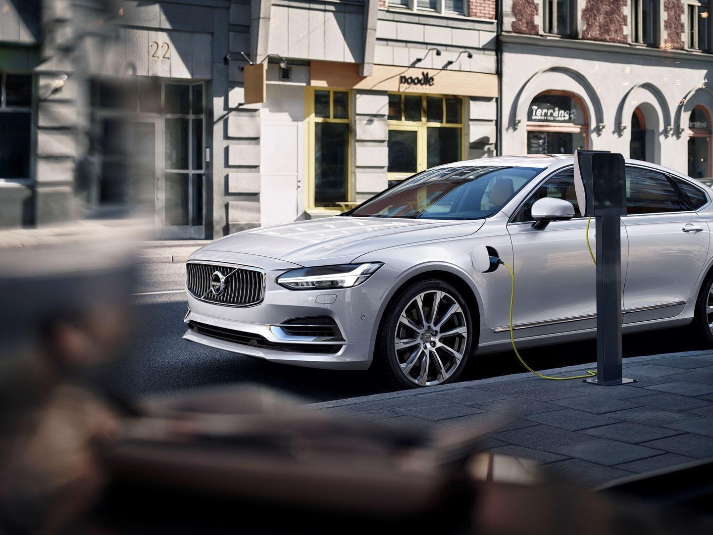 Volvo S90 en entorno urbano mostrando líneas estilizadas y detección de peatones.