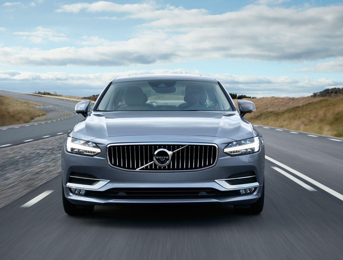 Imagen frontal del Volvo S90 en movimiento, mostrando su presencia en carretera.