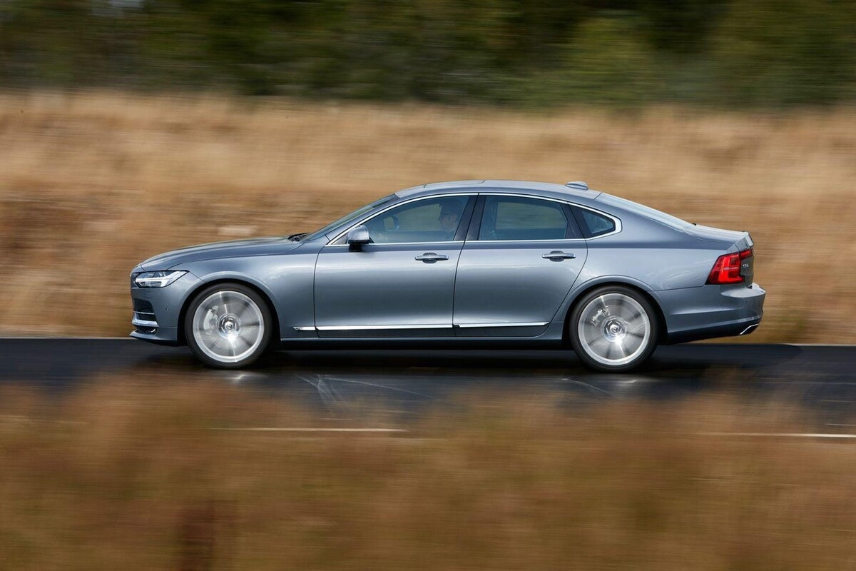 Volvo S90 en movimiento mostrando su perfil lateral y diseño elegante. Volvo S90 en movimiento mostrando su perfil lateral y diseño elegante.