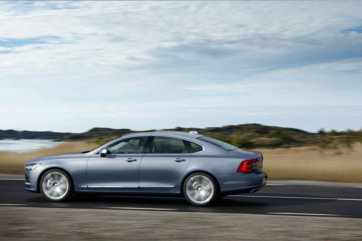 Volvo S90 captado de lado en movimiento, subrayando su presencia en la carretera.