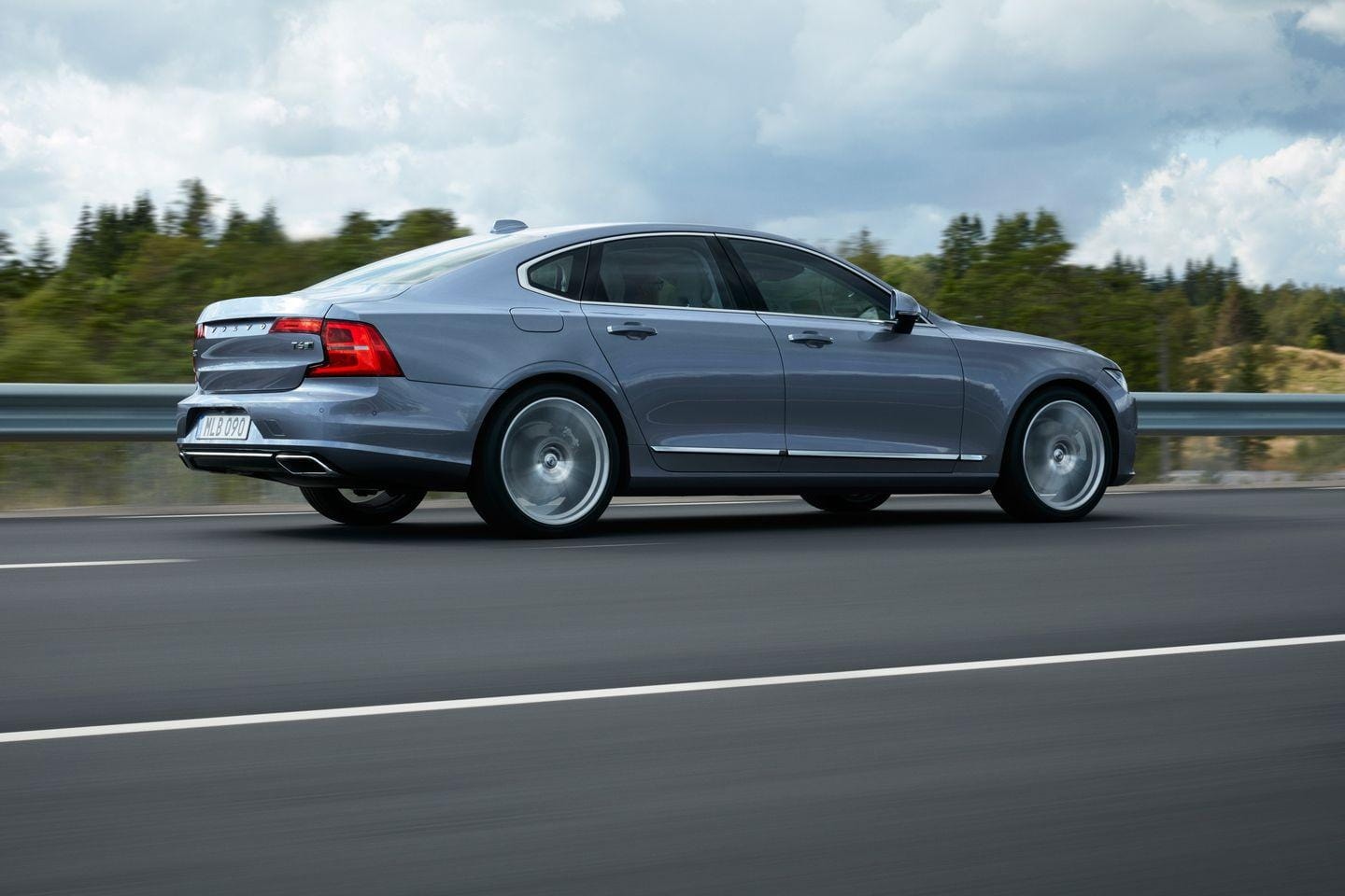 Vista lateral y trasera del Volvo S90 en movimiento, mostrando su diseño fluído.