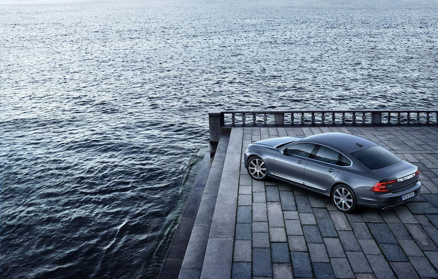 Trasera del Volvo S90 junto al mar, integrándose con la serenidad del muelle.