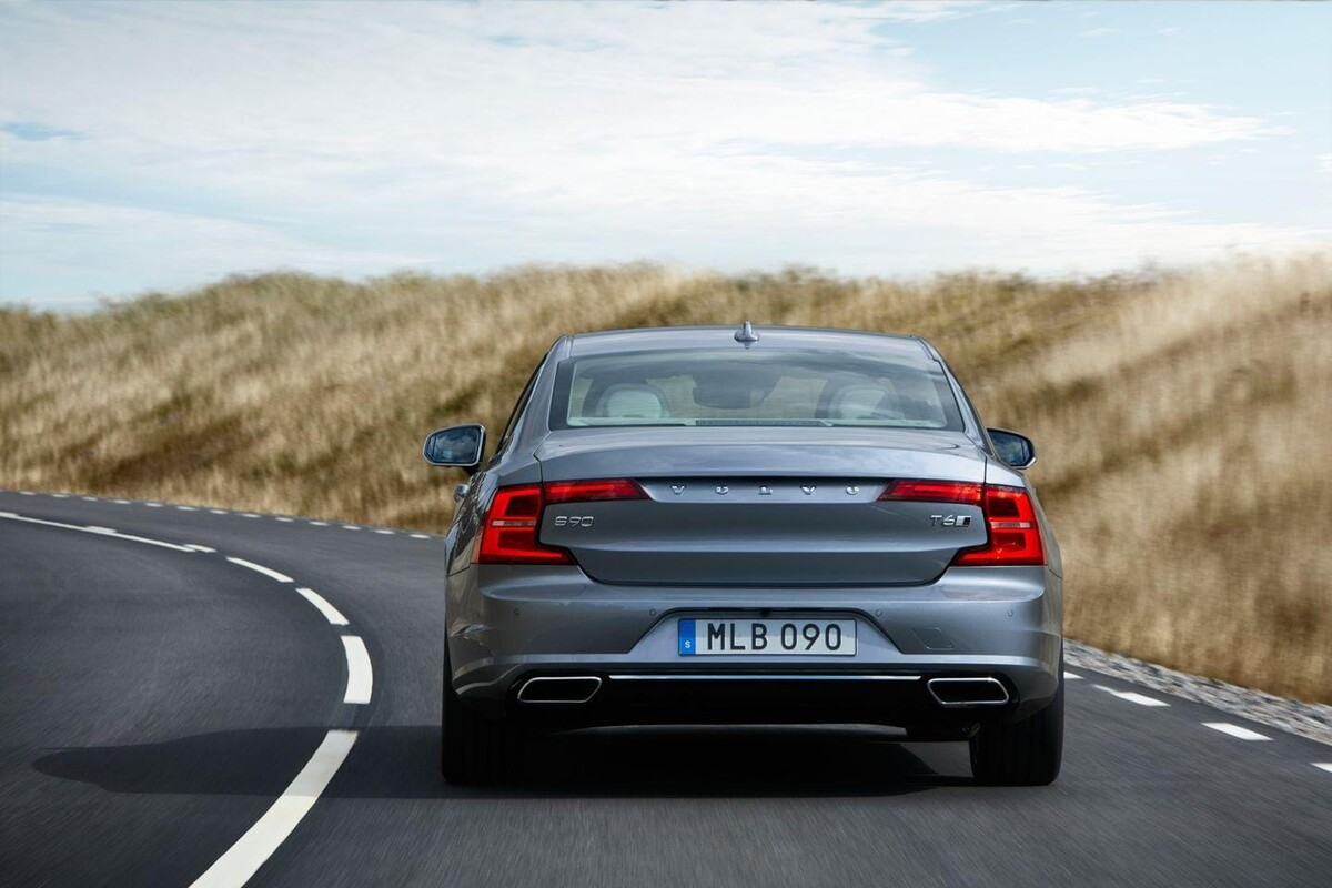 Imagen del Volvo S90 desde atrás en carretera, destacando su diseño de luces. Imagen del Volvo S90 desde atrás en carretera, destacando su diseño de luces.
