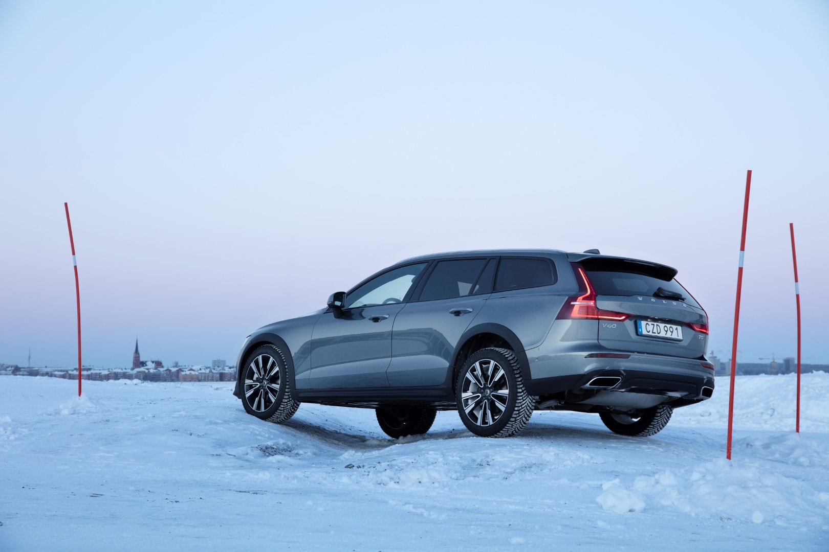 Trasera lateral del V60 Cross Country con el reflejo del atardecer en la nieve.