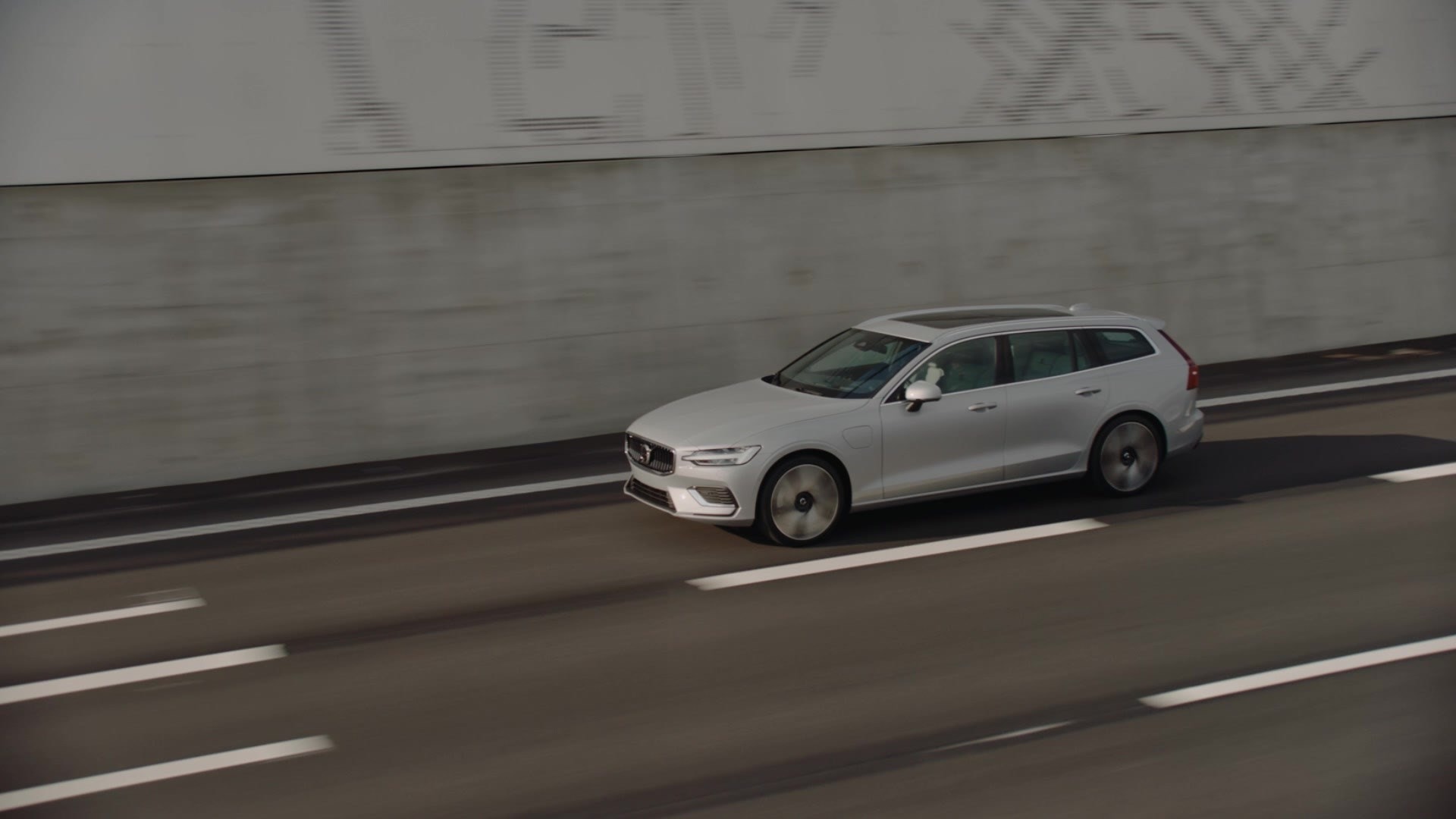 Volvo V60 híbrido capturado con dinamismo en una carretera urbana.