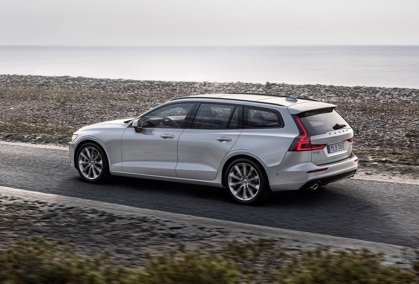 Volvo V60 transitando por la costa, resalta su diseño trasero y dinamismo.