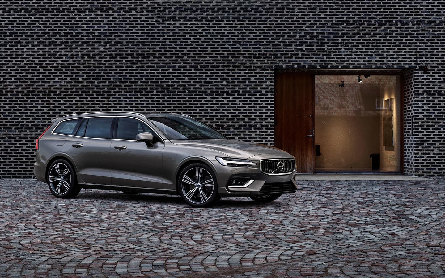 Volvo V60 perfilado ante una fachada moderna, combinación de estilo y tecnología.