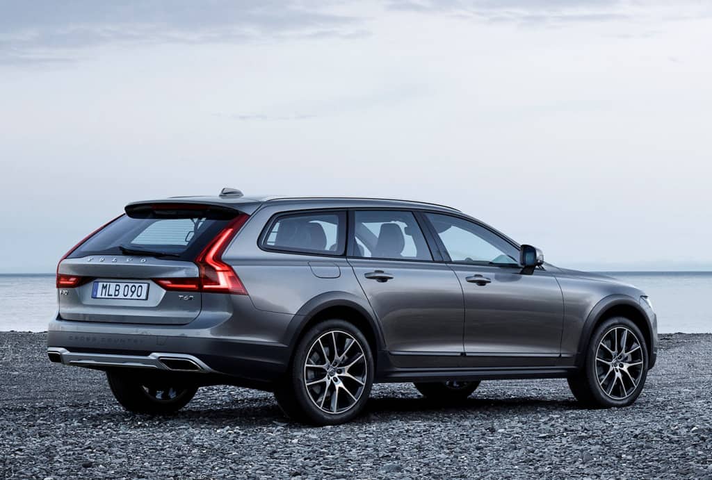 Vista trasera lateral del Volvo V90 Cross Country aparcado junto al mar.
